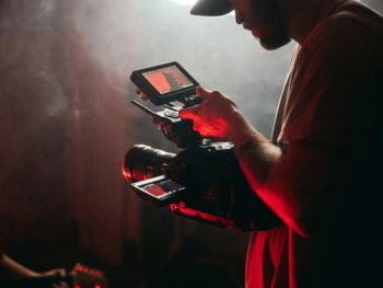 man in white t-shirt holding black video camera